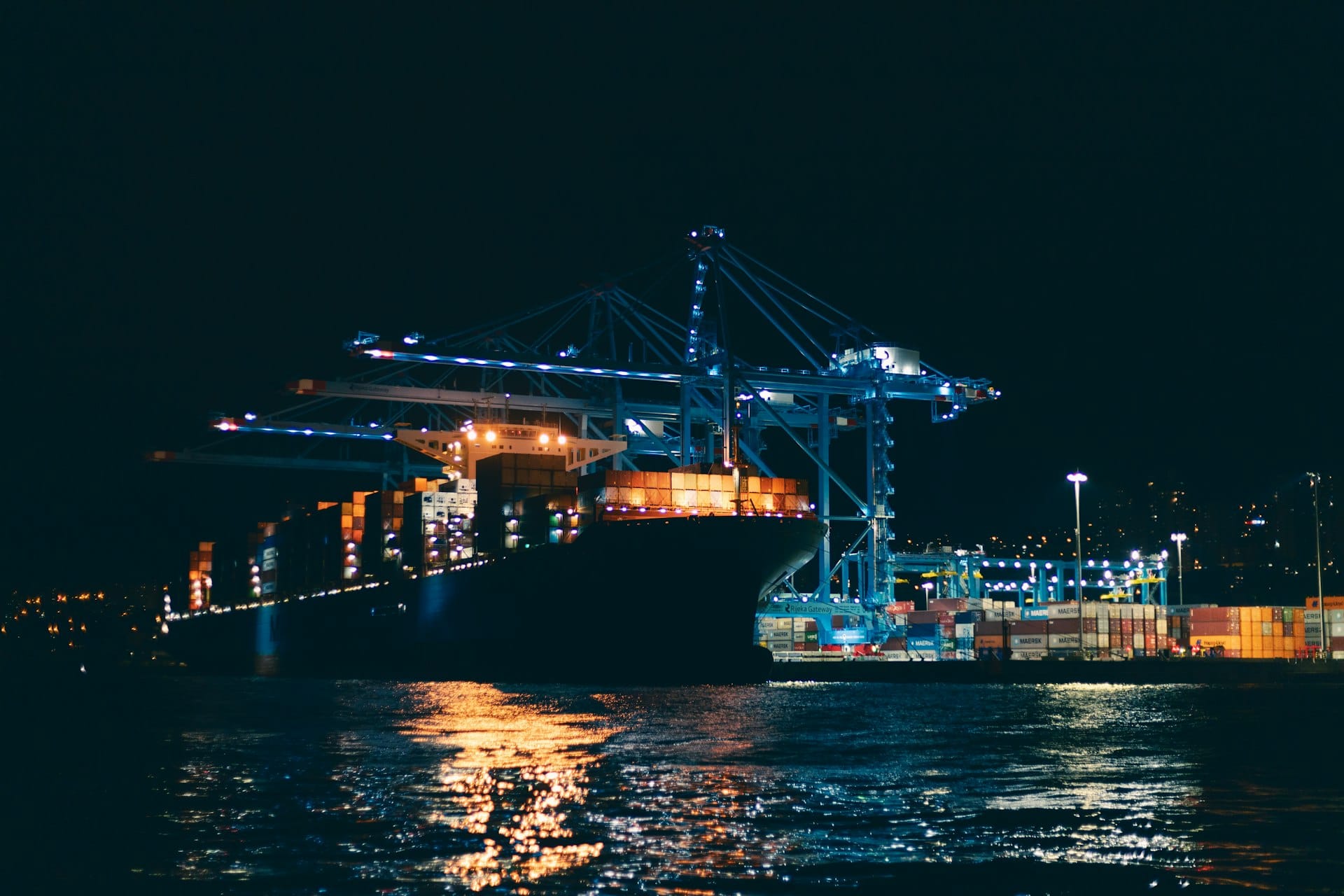 Container vessel alongside an illuminated gantry crane at night